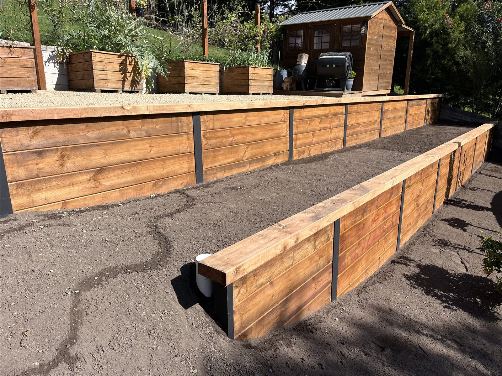 Two-tier timber retaining walls with steel posts and a garden shed above