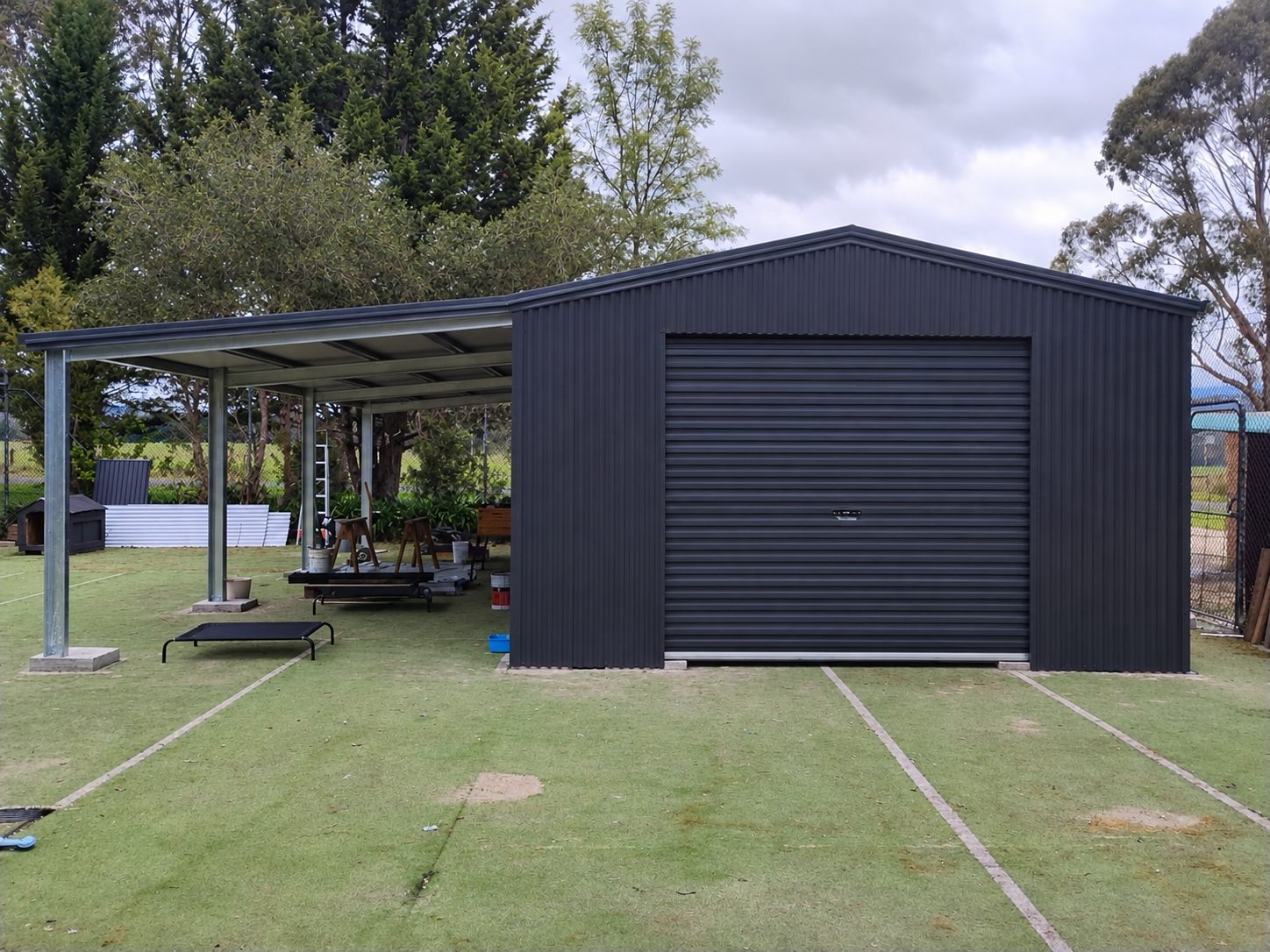 Black shed with attached carport and roller door