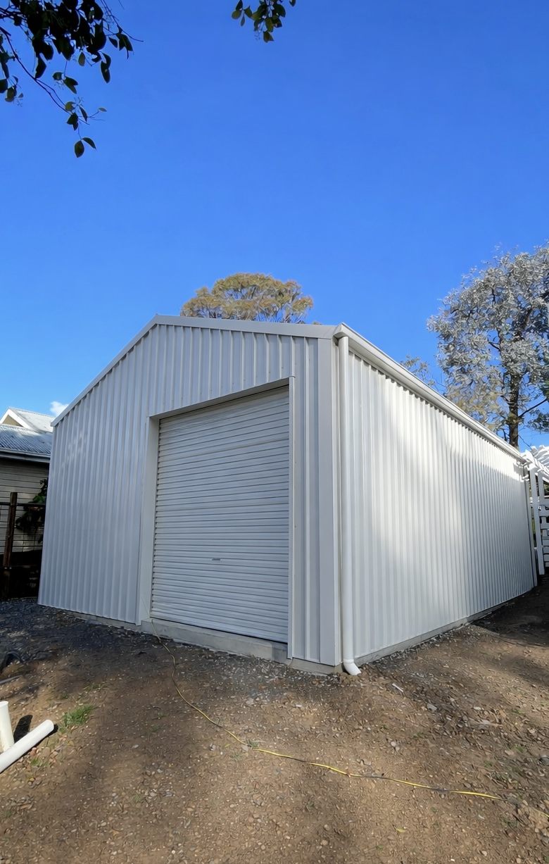 White shed with roller door and downpipe