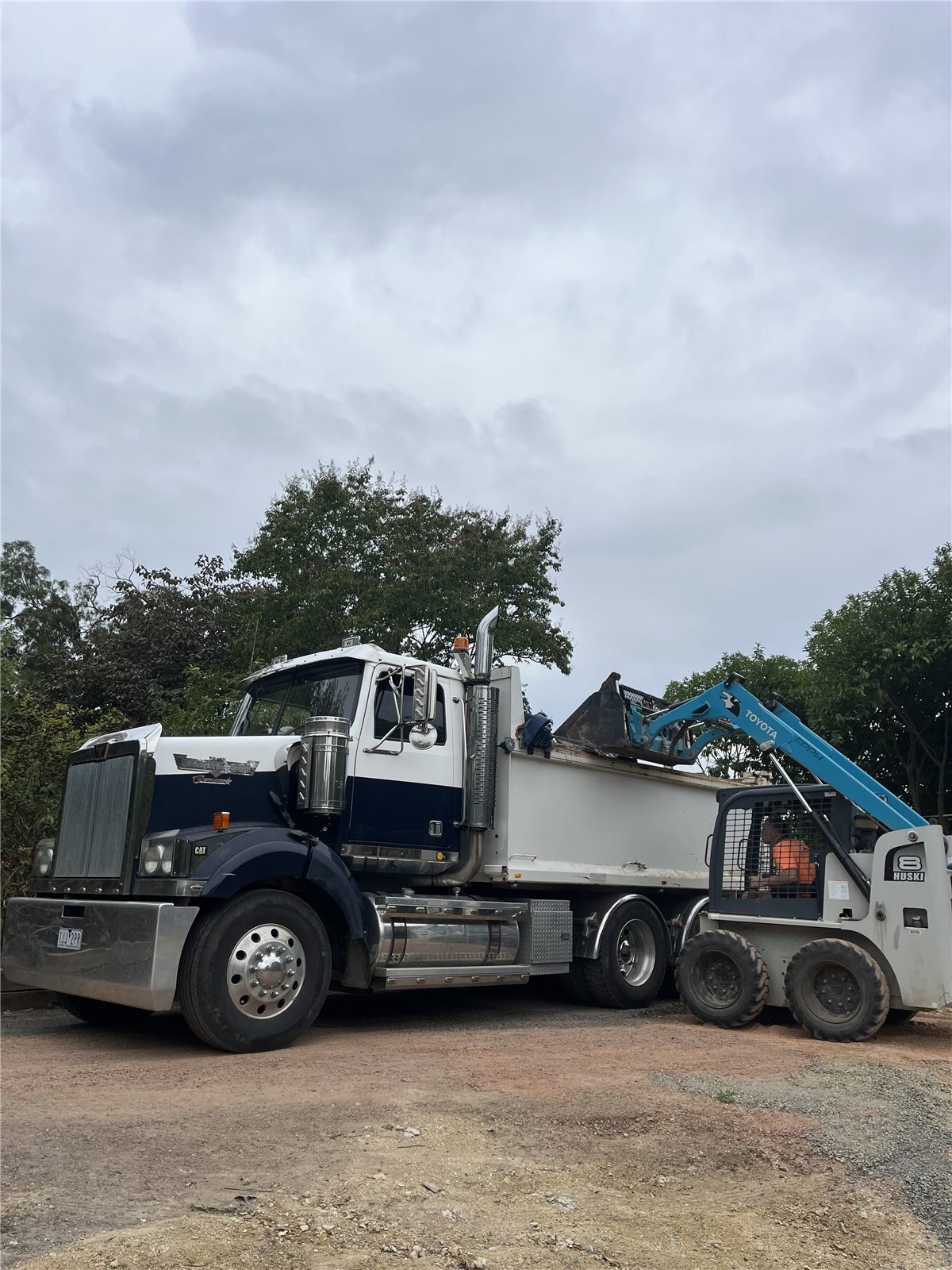 Tipper truck being loaded by a skid-steer loader